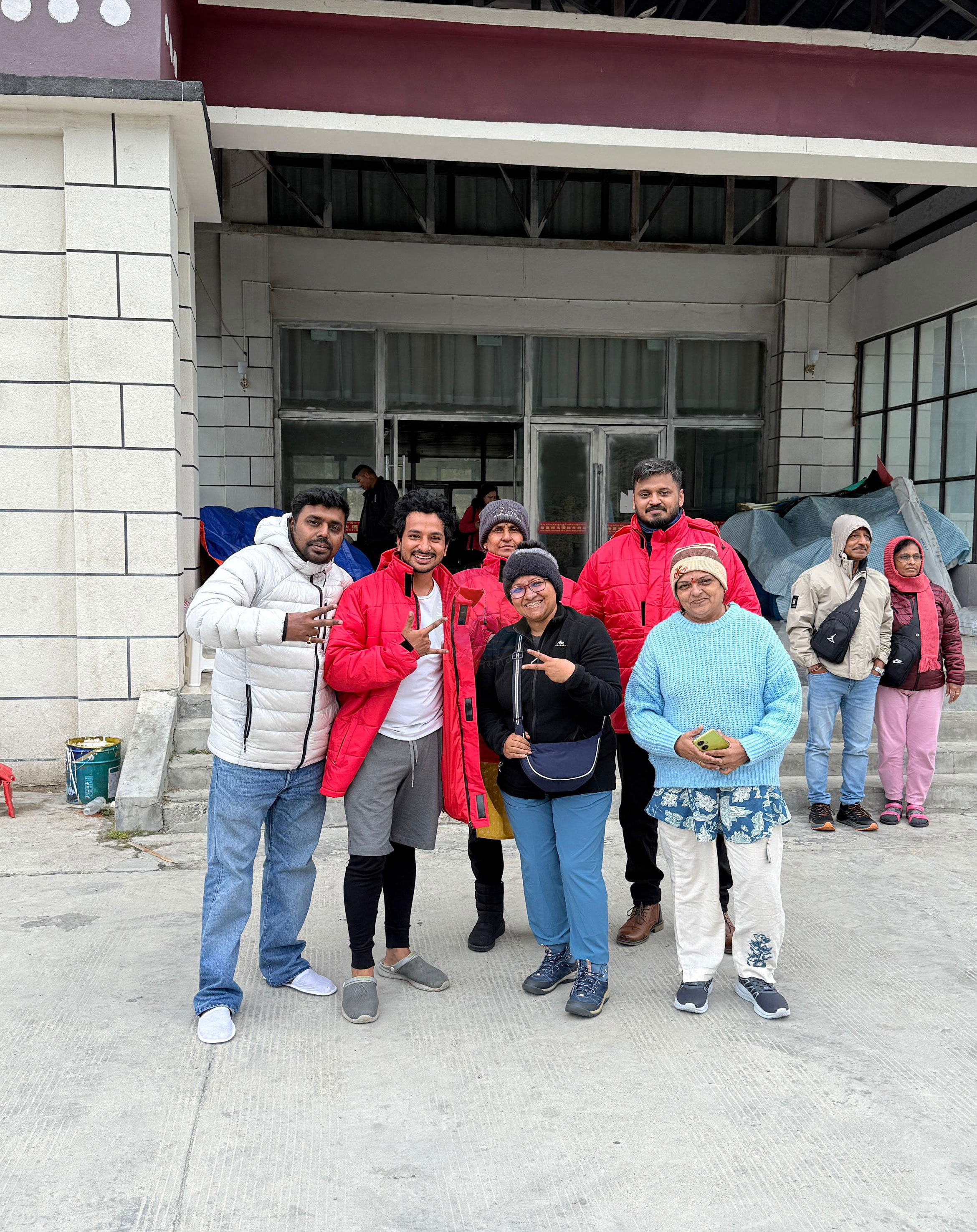 Pilgrims standing near resting places during Kailash Yatra, smiling and embracing the spirit of camaraderie in cold winds