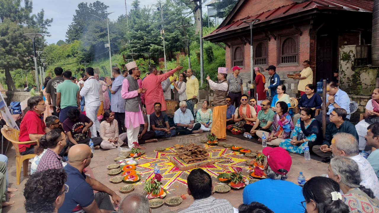 Devotees in a high-altitude Nepalese temple gather around a firepit and mandala, offering prayers and incense during a vibrant religious ceremony, with smoke rising into the air.