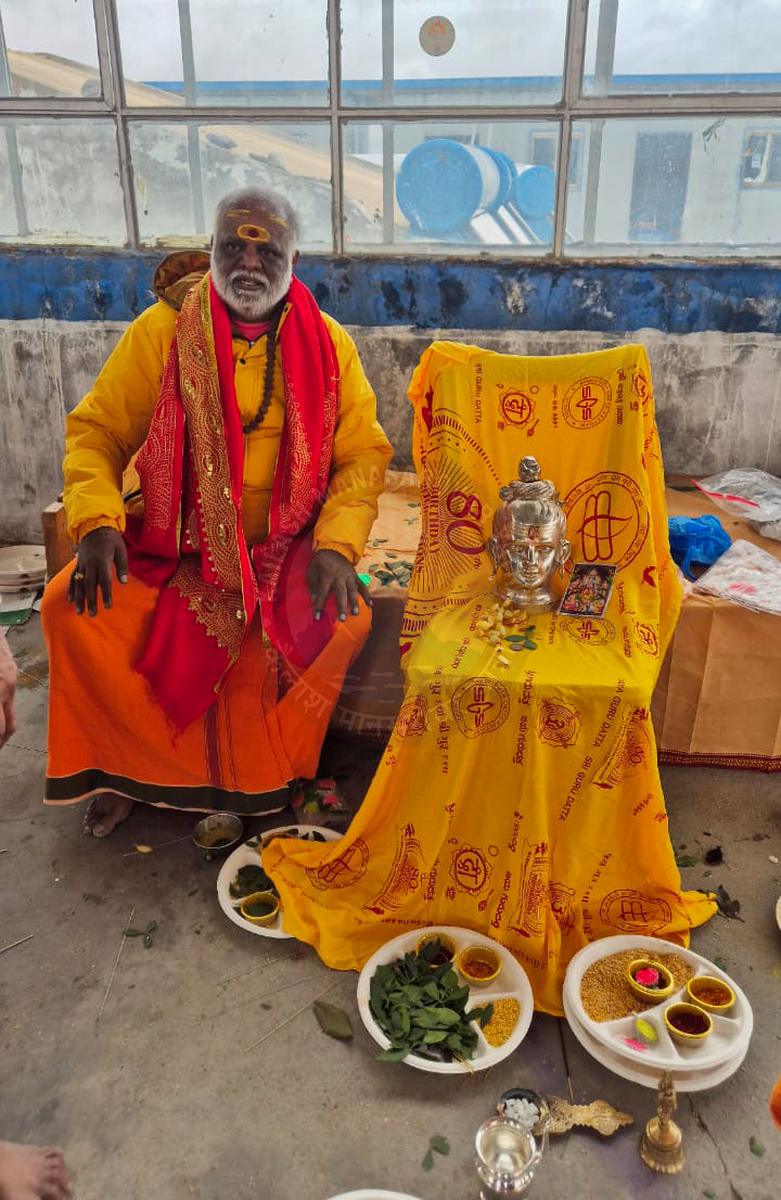 Respected Yatra Pandit Ji seated by a ritual altar at Kailash Mansarovar, dressed in saffron, guiding pilgrims through a profound spiritual journey.