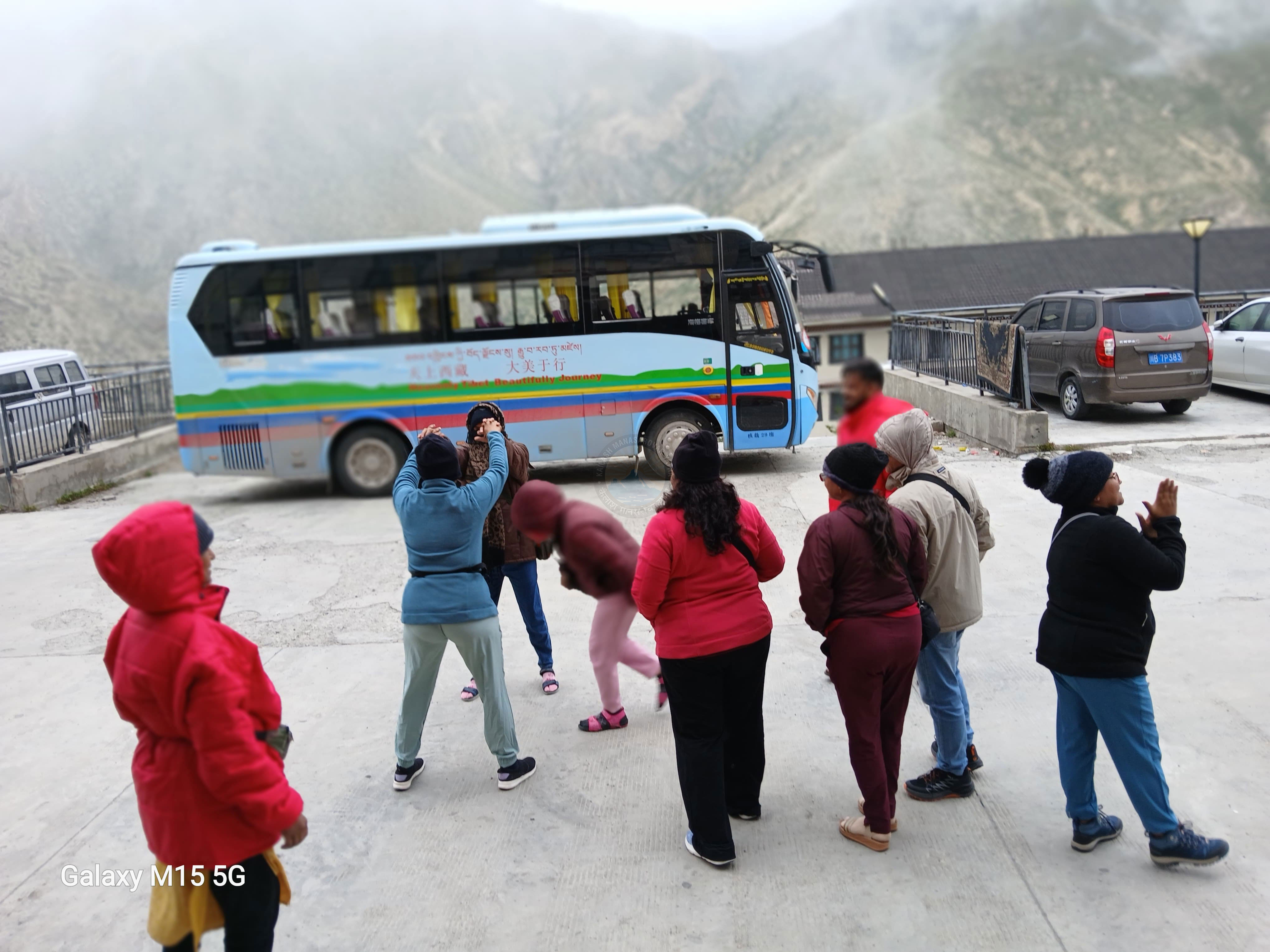 Group of travelers laughing and sharing moments on the Tibetan highlands with foggy mountain peaks in the background