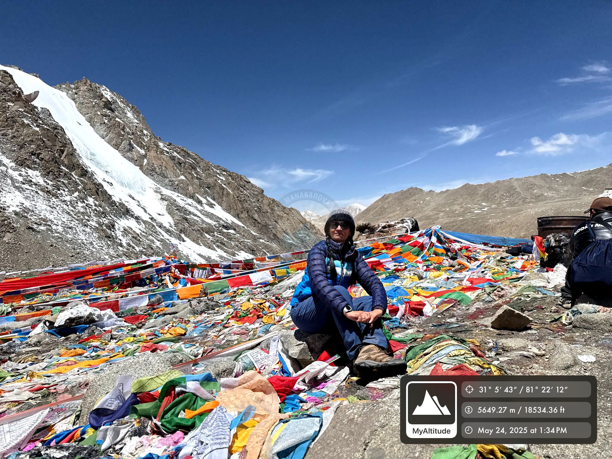 Pilgrims on the Kailash Yatra surrounded by snow-capped mountains and colorful prayer flags, experiencing peace and spiritual connection.