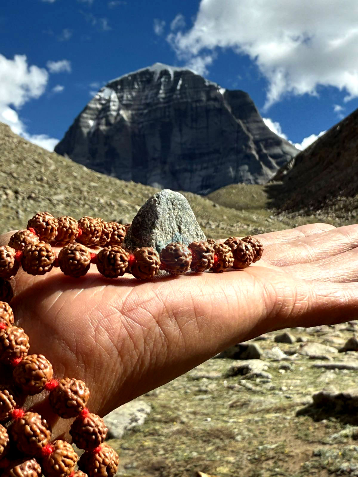 A devotee offering a Rudraksha mala before the majestic Mount Kailash, symbolizing deep faith and spiritual reverence on the sacred yatra.